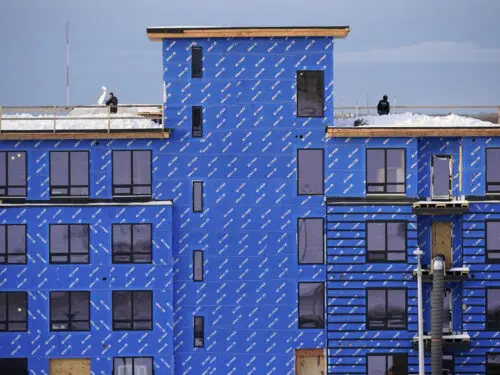 Workers remove snow from the roof of a condominium being constructed, Wednesday, Jan. 25, 2023, in Portland, Maine.